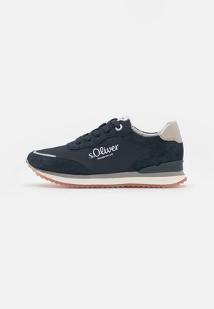 Marineblaue Sneakers mit einem Obermaterial aus Wildleder und Stoff, weißem Logo, beigen Akzenten und einer strukturierten Gummisohle mit rosafarbenem Unterrand.