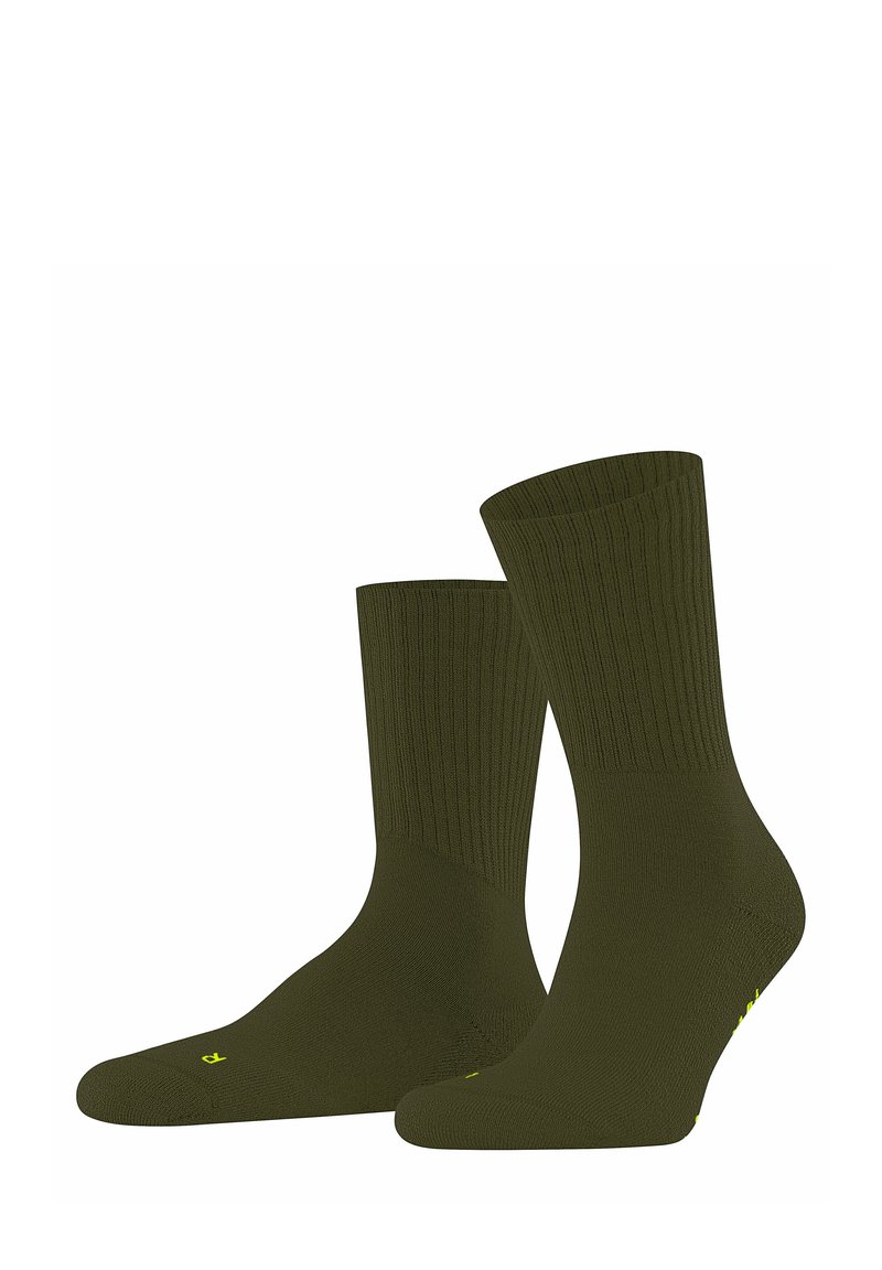 Chaussettes côtelées vert olive exposées debout, mettant en valeur leur texture lisse et leur léger éclat, avec un petit logo jaune sur le côté.