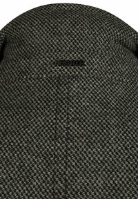 Grijze en zwarte gebreide beanie met textuur, met een zichtbaar logo-label en een afgeronde bovenkant, gemaakt van een dikke, warme stof.