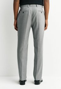 Gray checkered trousers with a tapered fit, rear pockets, and black footwear. The fabric features a small houndstooth pattern.