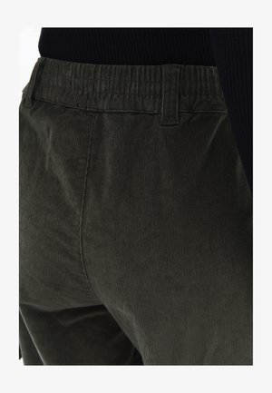 Donkergroene corduroy broek met een ribbelstructuur, voorzien van een elektrische tailleband en zijzakken. Middenhoogte pasvorm, met focus op de details aan de achterkant.