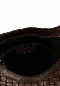 Open bruine geweven leren tas met een donker stoffen interieur, voorzien van een ritsvak en een genaaide leren label binnenin.