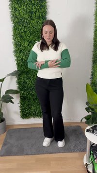 Maglione lavorato a maglia in crema e verde, con texture a coste e maniche lunghe, abbinato a pantaloni neri a palazzo e sneakers bianche.