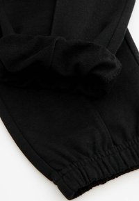 Czarne spodnie na elastycznej talii wykonane z miękkiej bawełny. Posiadają marszczony, falbaniasty detal na dole i gładką fakturę.