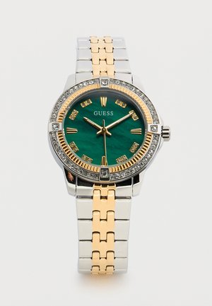 Two-tone metal Guess wristwatch with green face, gold Roman numeral markers, crystal accents on bezel, and linked bracelet band.