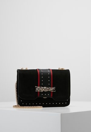 Czarna aksamitna torebka na ramię z czerwonymi paskami, srebrnymi ćwiekami, złotym łańcuszkiem i ozdobną złotą klamrą w kształcie głowy lamparta.