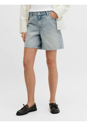 Svetlomodré riflové šortky nosené s bielym topom a svetlo pruhovanou košeľou, v kombinácii s čiernymi šnurovacími mokasínmi na jednoduchom pozadí.