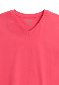 T-shirt z dekoltem w serek w jasnoróżowym kolorze, wykonany z miękkiej bawełny. Posiada gładką fakturę i prosty design, a metka marki widoczna jest wewnątrz dekoltu.