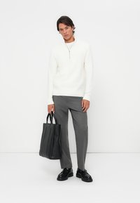 White zip-up sweater, grey tailored pants, black tote bag with structured design, and black chunky shoes. Minimalist style with clean lines.