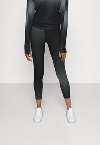 Leggings athletic neri con un design a gradiente, abbinati a un top a maniche lunghe coordinato. Entrambi presentano un tessuto liscio e elasticizzato.