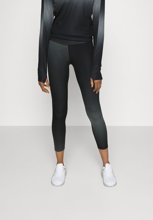 Leggings de sport noirs avec un design dégradé, accompagnés d'un haut à manches longues assorti. Les deux présentent un tissu lisse et extensible.