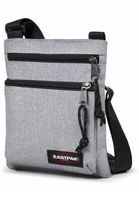 Borsa a tracolla grigia in tessuto con due scomparti con zip, zip nere, tracolla regolabile e patch del logo Eastpak sul davanti.