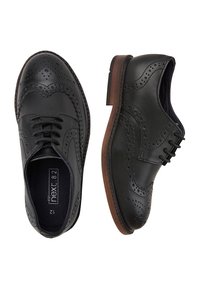 Chaussures brogues en cuir noir avec perforations décoratives, design à lacets et semelle contrastante marron. Texture lisse avec des détails classiques.