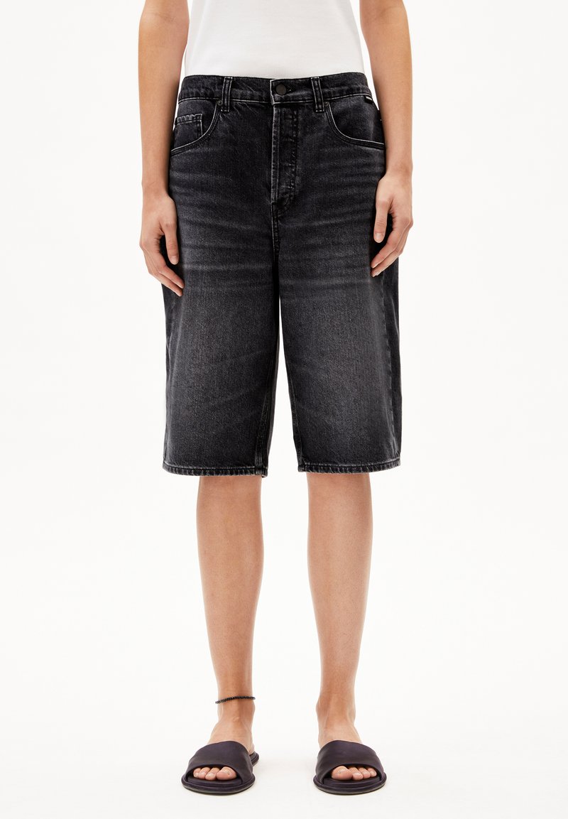 Donkergrijze denim bermuda shorts met een relaxed fit, voorzien van zakken, riemlussen en een ruwe zoom. Draagt met zwarte slippers.