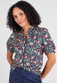 Blusa floreale con maniche a palloncino corte, sfondo blu navy, motivi di fiori rosa e verdi, chiusura frontale con bottoni, tessuto leggero.