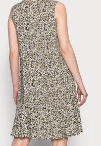 Robe sans manches à imprimé floral avec un col rond. Présente un dos à découpe en trou de serrure, un bas évasé et un mélange de couleurs vert, blanc et noir.