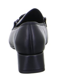 Scarpa nera in pelle con tacco a blocco di media altezza, texture liscia, design curvo e silhouette elegante con dettaglio della fascia.