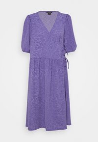 Robe violette en tissu léger, avec un col en V, des manches bouffantes et un motif à pois. Comprend un détail de nouage à la taille.