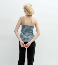 Top sin tirantes con un patrón tejido en azul y blanco, con una silueta ajustada y una tela texturizada. El modelo lleva pantalones de pierna ancha negros.