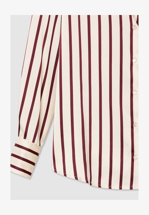 Bluzka w kolorze kremowym z pionowymi bordowymi paskami, z zapięciem na guziki i mankietami. Gładka struktura tkaniny.