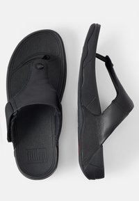 Tongs noires en cuir texturé avec un entredoigt, dotées d'un semelle intérieure rembourrée et d'une semelle en caoutchouc plate.
