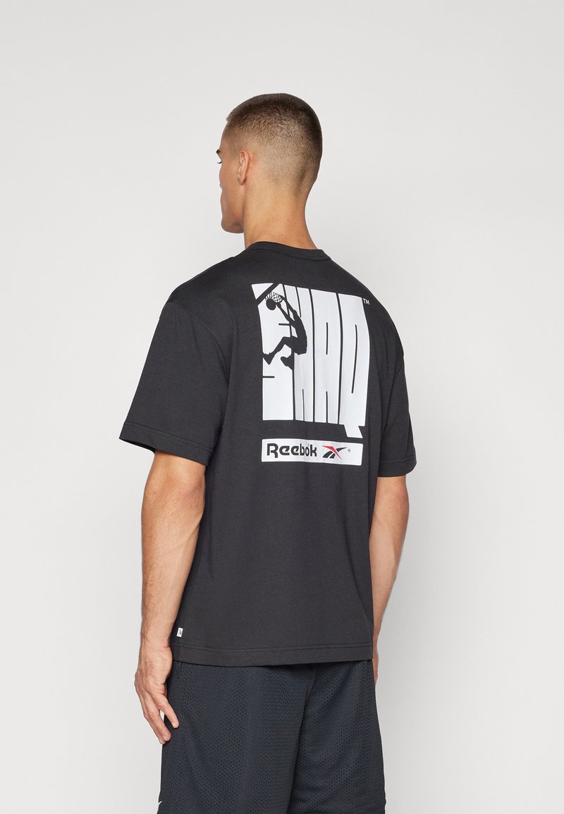 Must musta t-särk mustas toonis, millel on suur valge kujutis korvpallurist ja tekst "SHAQ", Allpool on "Reebok" logo. Lühikesed varrukad.