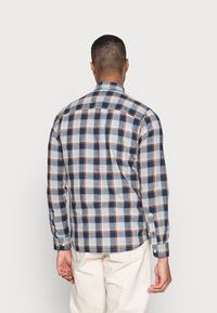 Camisa de cuadros en tonos azules, blancos y naranjas. Mangas largas, cuello abotonado y puños abotonados. Material de algodón con una textura suave.