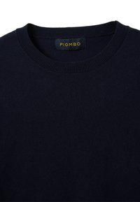Maglione lavorato a maglia blu navy con scollo rotondo e colletto a coste. Presenta un'etichetta con la scritta "PIOMBO" ricamata in filo giallo. Tessuto morbido e testurizzato.