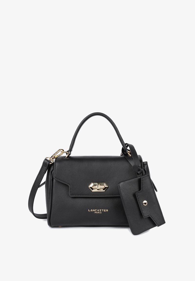 Sac à main en cuir noir au design structuré, avec des accessoires en or et une étiquette amovible. Il dispose d'une poignée supérieure et d'une bandoulière réglable.