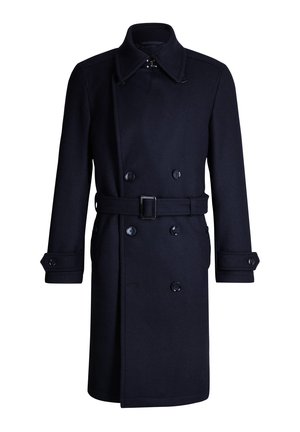 Manteau en laine bleu marine à double boutonnage avec large col, ceinture à boucle rectangulaire et poignets boutonnés, présenté sur un fond blanc.