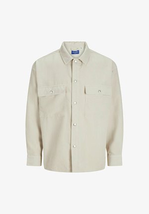 Kermanvärinen kauluspaita, joka on valmistettu ribbikankaasta. Paidassa on kaksi rintataskua läpillä ja hopeanvärisillä napitusnapeilla. Yksinkertainen kaulus ja pitkät hihat.