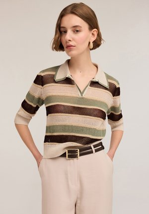 Trui in polo-stijl met groene, beige en bruine horizontale strepen. Korte mouwen en kraag met een lichte v-hals. gedragen met een riem.