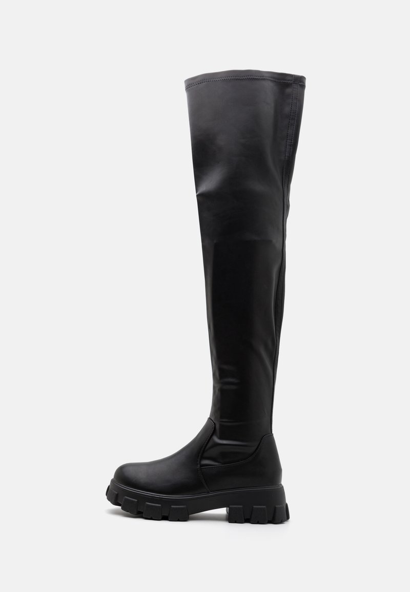 Botte haute en cuir noir avec semelle épaisse à crampons et finition lisse, conçue pour une couverture jusqu'au genou et un style robuste.