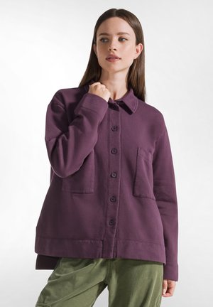 Giacca viola, con bottoni, colletto, due tasche frontali e maniche lunghe. Tessuto morbido con una vestibilità rilassata e un leggero dettaglio all'orlo.