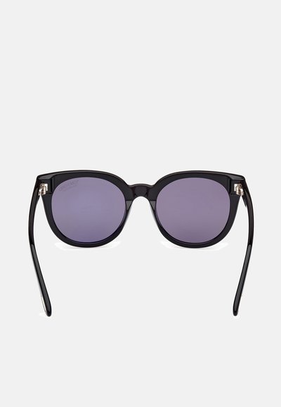 Lunettes de soleil noires en forme d'œil de chat avec des verres dégradés gris et des branches fines et élégantes. Présence de petites accents en métal près des charnières.