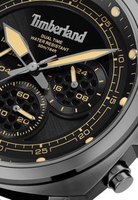 Orologio Timberland nero con funzione dual time. Cassa rotonda, dettagli in argento e oro, quadrante nero texturizzato e indici delle ore prominenti. Resistente all'acqua.