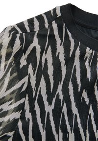 Tessuto a righe bianche e nere con una sensazione di texture, caratterizzato da un design a zigzag. Collo rotondo con bordo a costine nere.