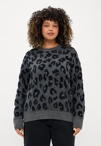 Suéter cinza com padrão de leopardo preto, tecido de malha texturizada, mangas largas e decote redondo, combinado com jeans escuros.