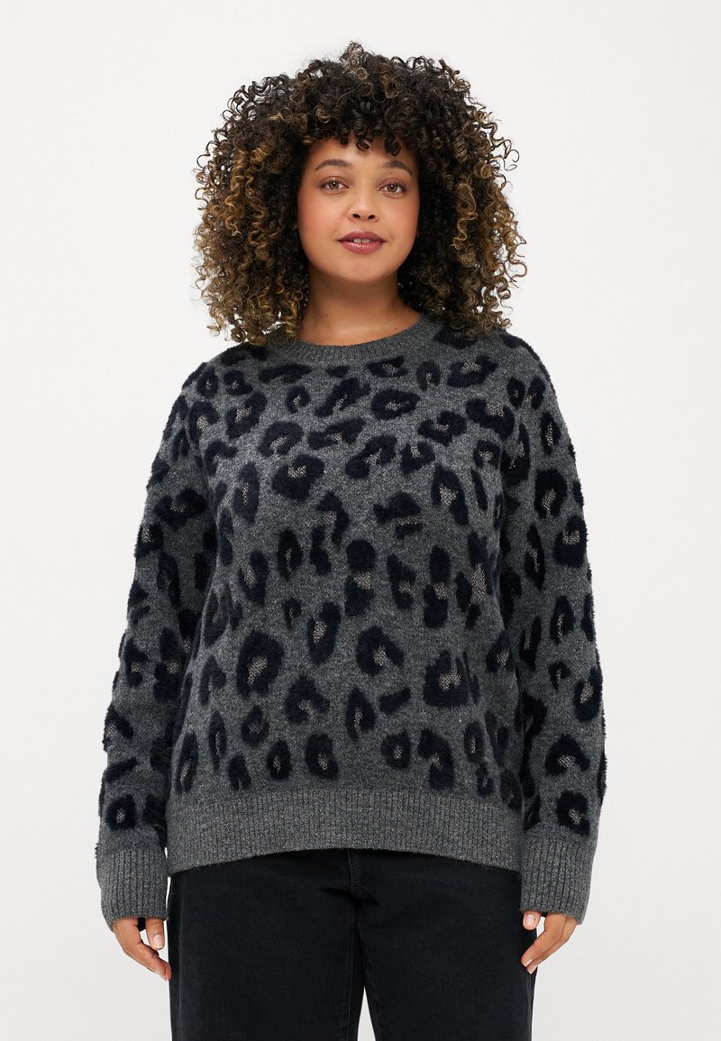 Suéter cinza com padrão de leopardo preto, tecido de malha texturizada, mangas largas e decote redondo, combinado com jeans escuros.