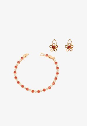 Kultainen rannekoru ja siihen sopivat kukkamuotoiset korvakorut, joissa on vuorotellen punaisia ja kirkkaita jalokiviä valkoisella taustalla.