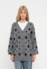 Grå cardigan med V-ringning, med svarta stjärnmönster, knappstängning och oversized ärmar. Mjuk textur.