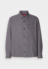Checkered long-sleeve shirt in navy and burgundy with a button-down collar, front pocket, and logo detail on chest.