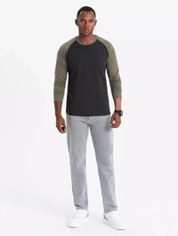 Langärmliges Raglanshirt mit schwarzem Körper und olivgrünen Ärmeln, kombiniert mit grauen Jeans und weißen Schuhen. Einfaches, lässiges Design und Passform.