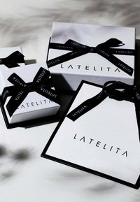 Three white gift boxes with black ribbon, featuring the brand name "LATELITA" in bold lettering, varying in size and shape.