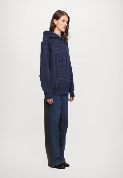 Navy hooded sweatshirt with a geometric stitching pattern, paired with wide-leg denim pants in dark and light blue hues.