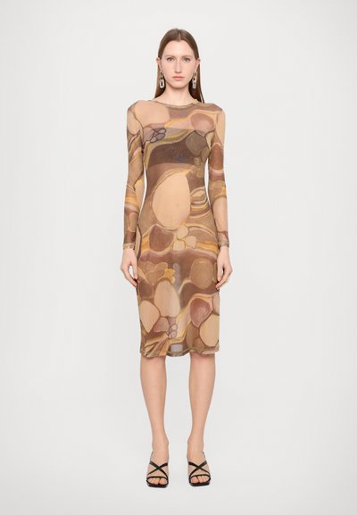Long-sleeve, translucent dress in warm tones with abstract circular patterns. Fitted shape, knee-length, paired with strappy black sandals.