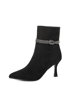 Stivale alla caviglia in suede nero con punta affusolata e tacco sottile. Presenta una banda decorativa intrecciata in tonalità argento attorno alla parte superiore. Texture liscia.