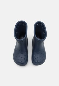 Bottes de pluie en caoutchouc bleu marine avec une finition lisse, hauteur à la cheville et trous de ventilation sur les côtés. Semelle texturée pour une meilleure adhérence.
