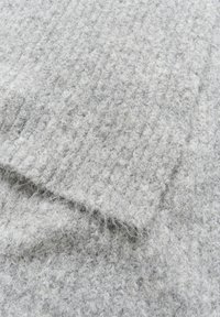 Tessuto grigio lavorato a maglia con un motivo testurizzato, caratterizzato da una superficie morbida e pelosa e da un design a coste, che crea profondità e interesse visivo.