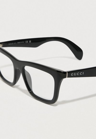 Zwarte Gucci zonnebril met een dik rechthoekig montuur, glanzende textuur en heldere glazen. Het logo is gegraveerd op de arm, met een slank ontwerp en subtiele accenten.